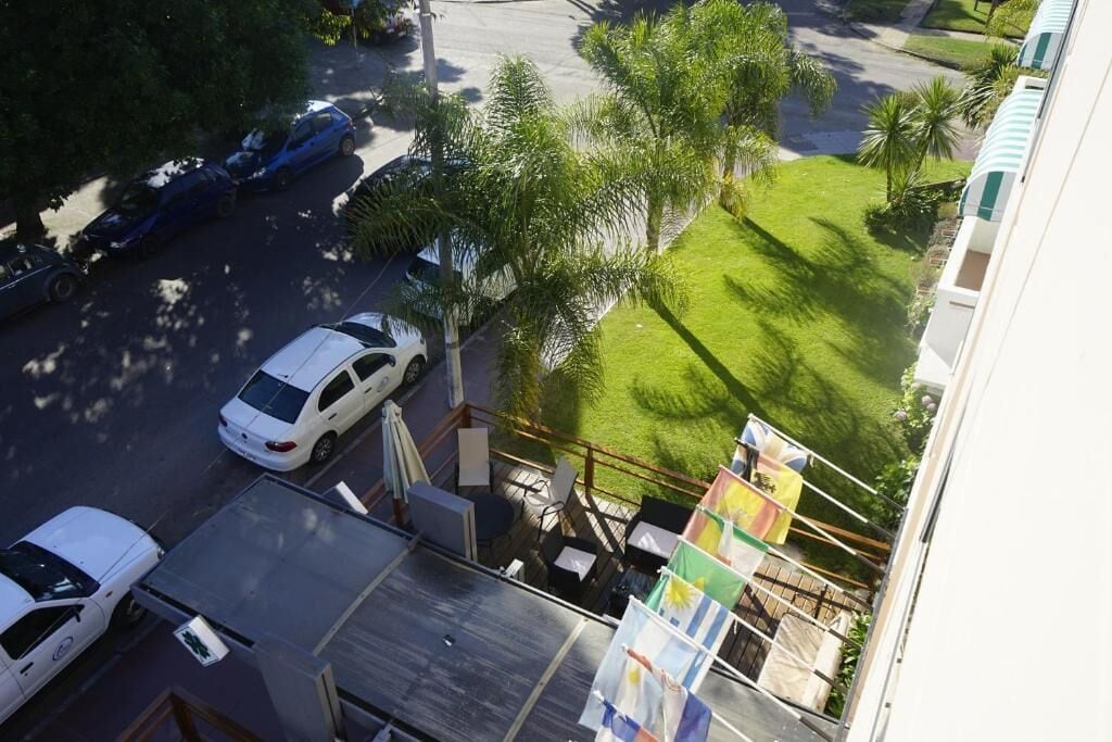 A residential area with parked cars, a grassy lawn, and a building with balconies.