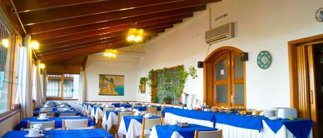 Un comedor con mesas dispuestas para una comida, con manteles azules y sillas de madera.