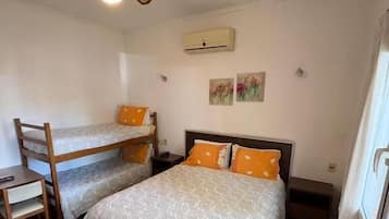 A bedroom with two beds, a ceiling fan, a small table, and a window.