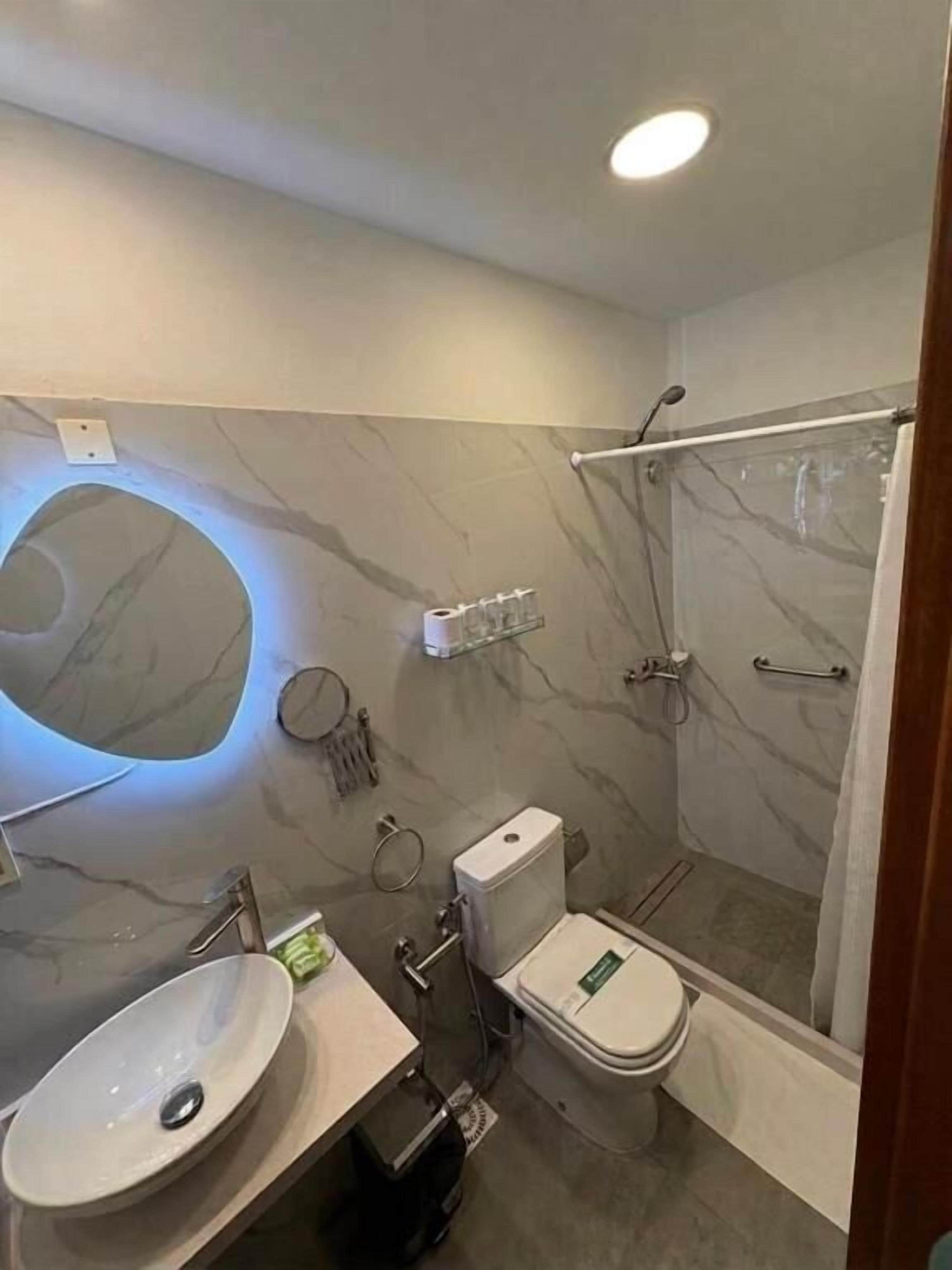Een moderne badkamer met een marmeren wastafelmeubel, toilet en douchecabine.