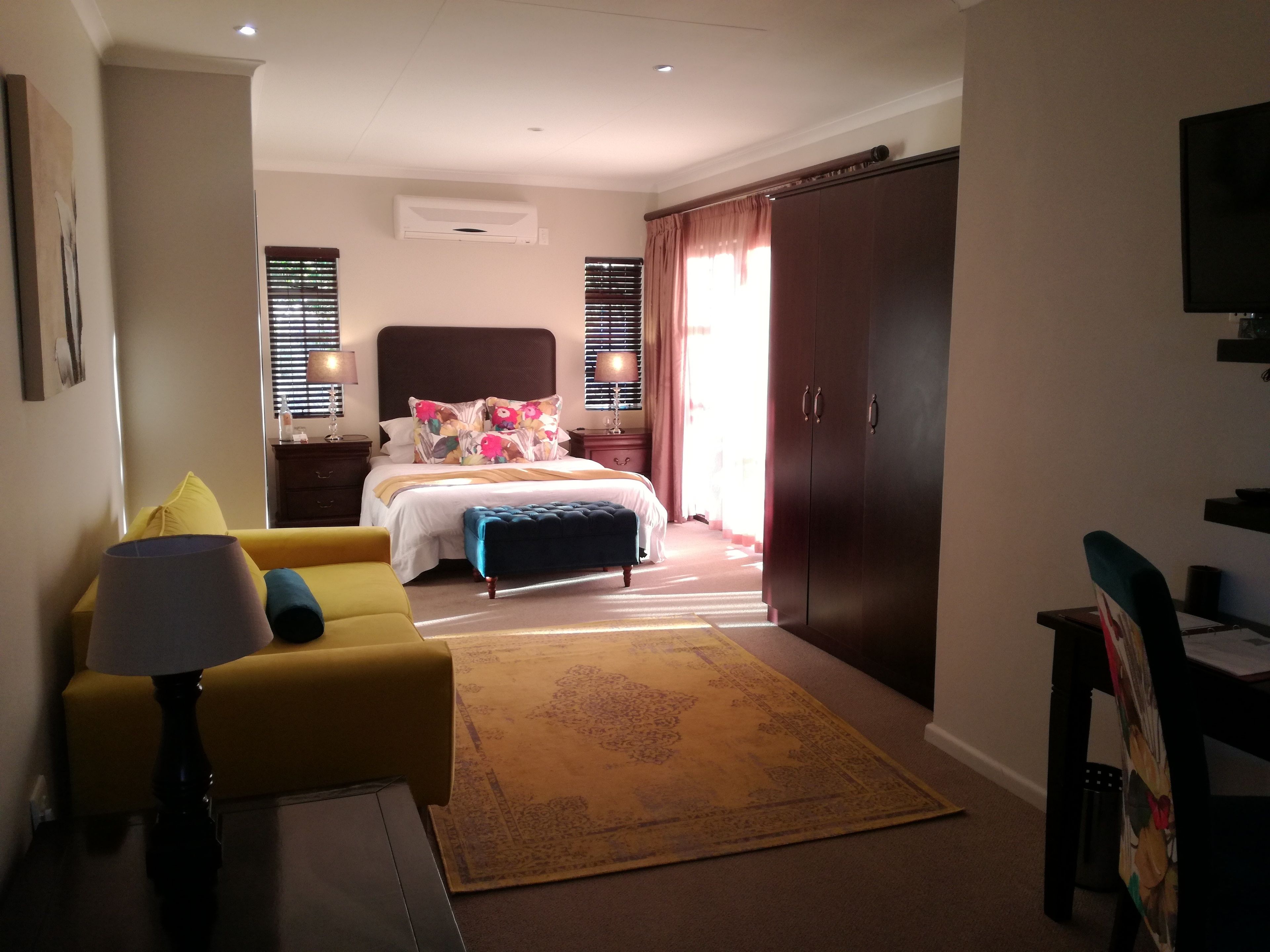 A hotel room with a bed, a desk, a chair, a sofa, and a wardrobe.