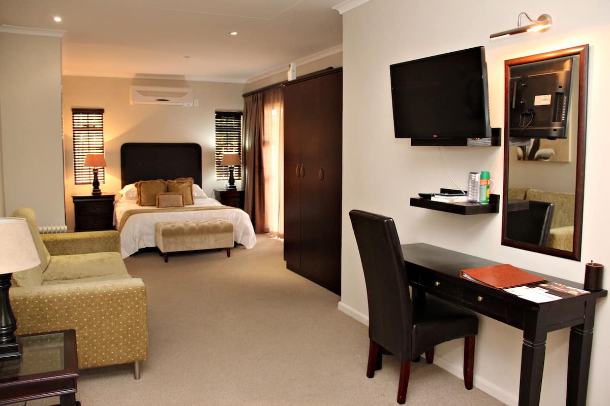 Habitación de hotel con cama, escritorio, silla, televisor y armario.
