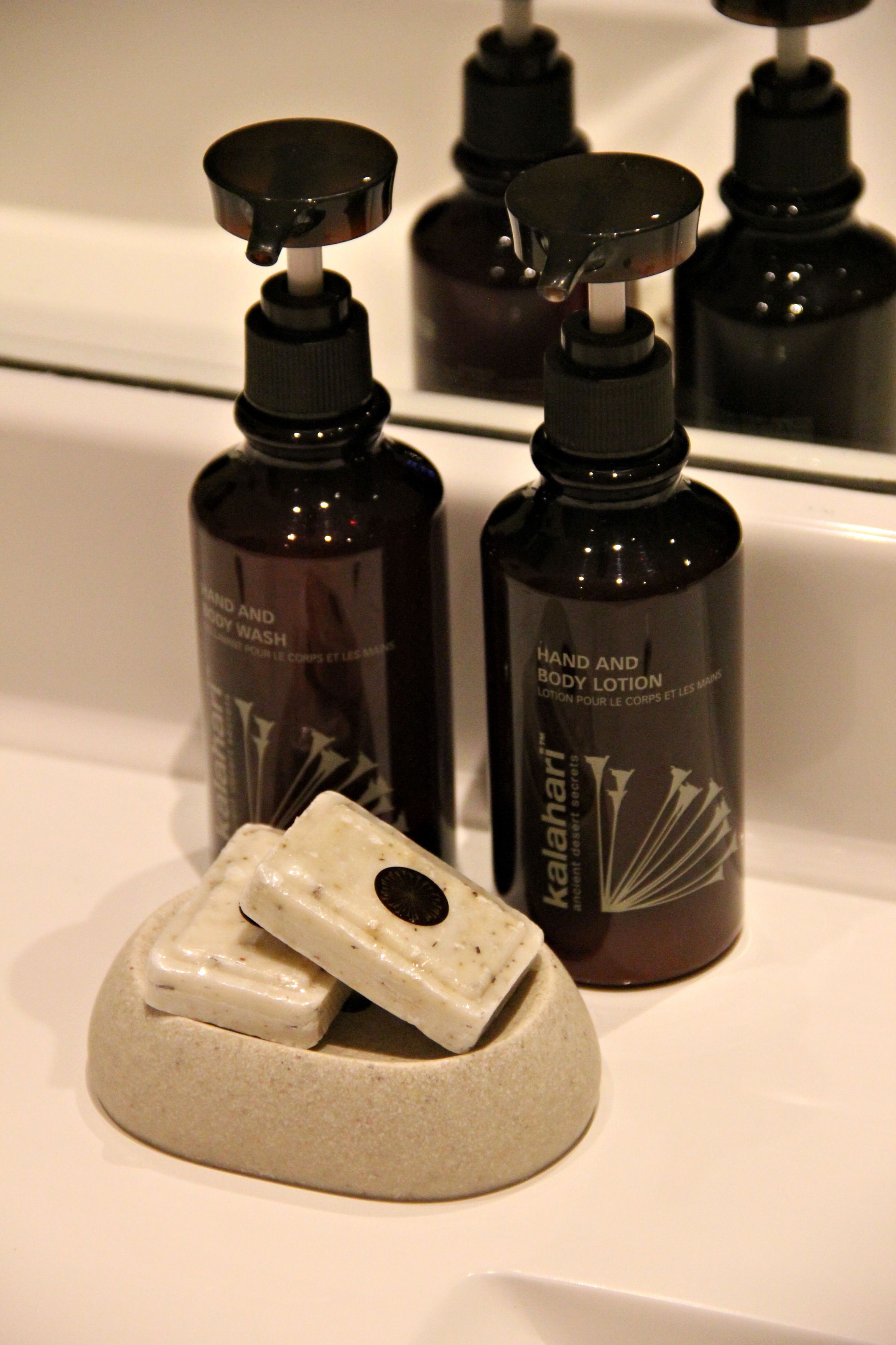 A bathroom with a white sink, a soap dish, and several bottles of hand and body lotion.