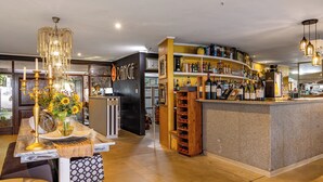 Een bar met een toog, flessenplanken en een kroonluchter.