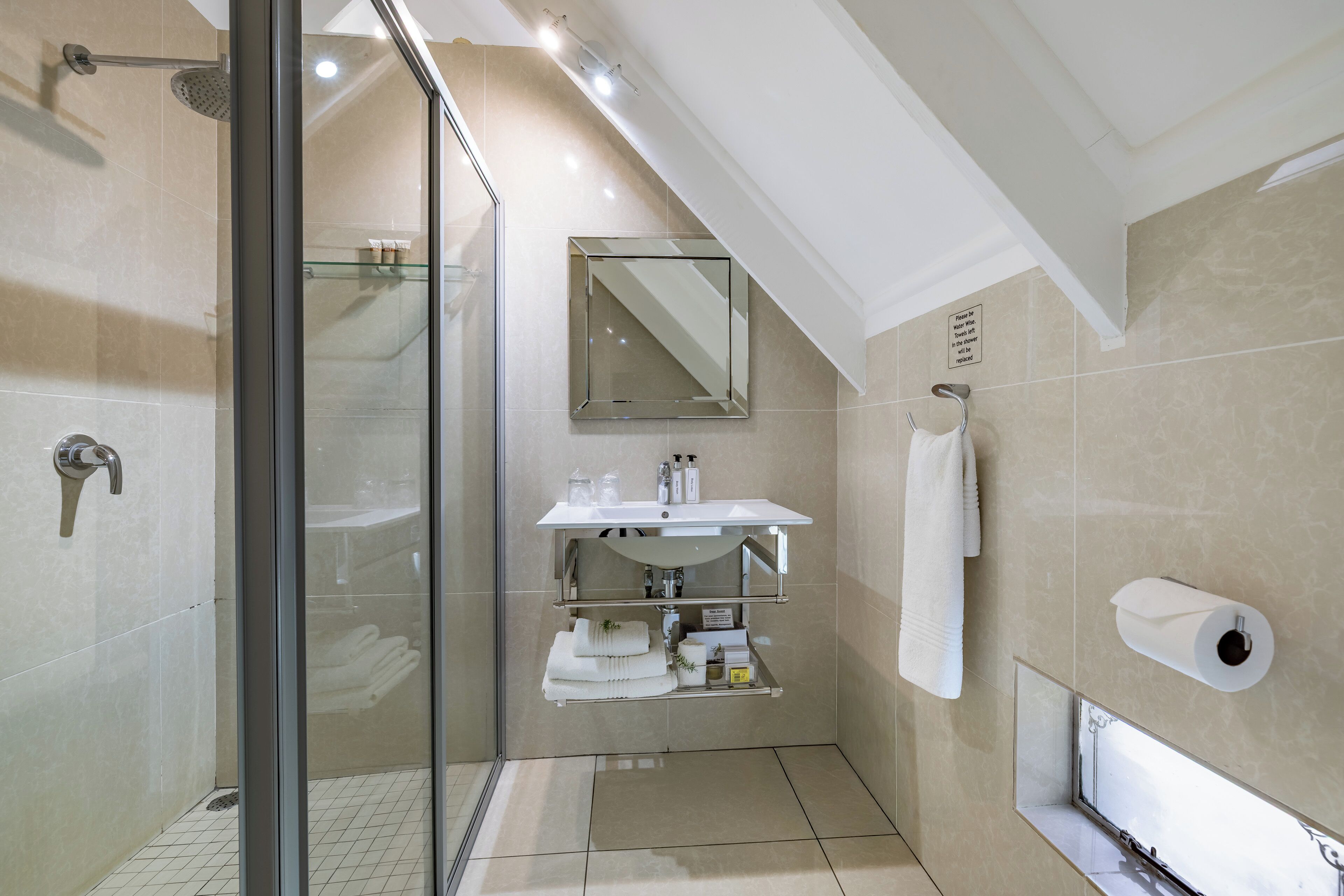 A modern bathroom with a glass shower enclosure, a built-in sink with a mirror, and a towel rack.