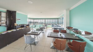 Un comedor con barra libre, sillas y vistas a la ciudad.