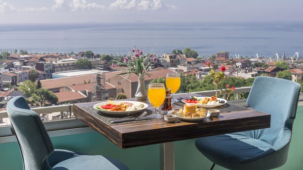 Un balcón con una mesa lista para el desayuno, con vistas a una ciudad costera.