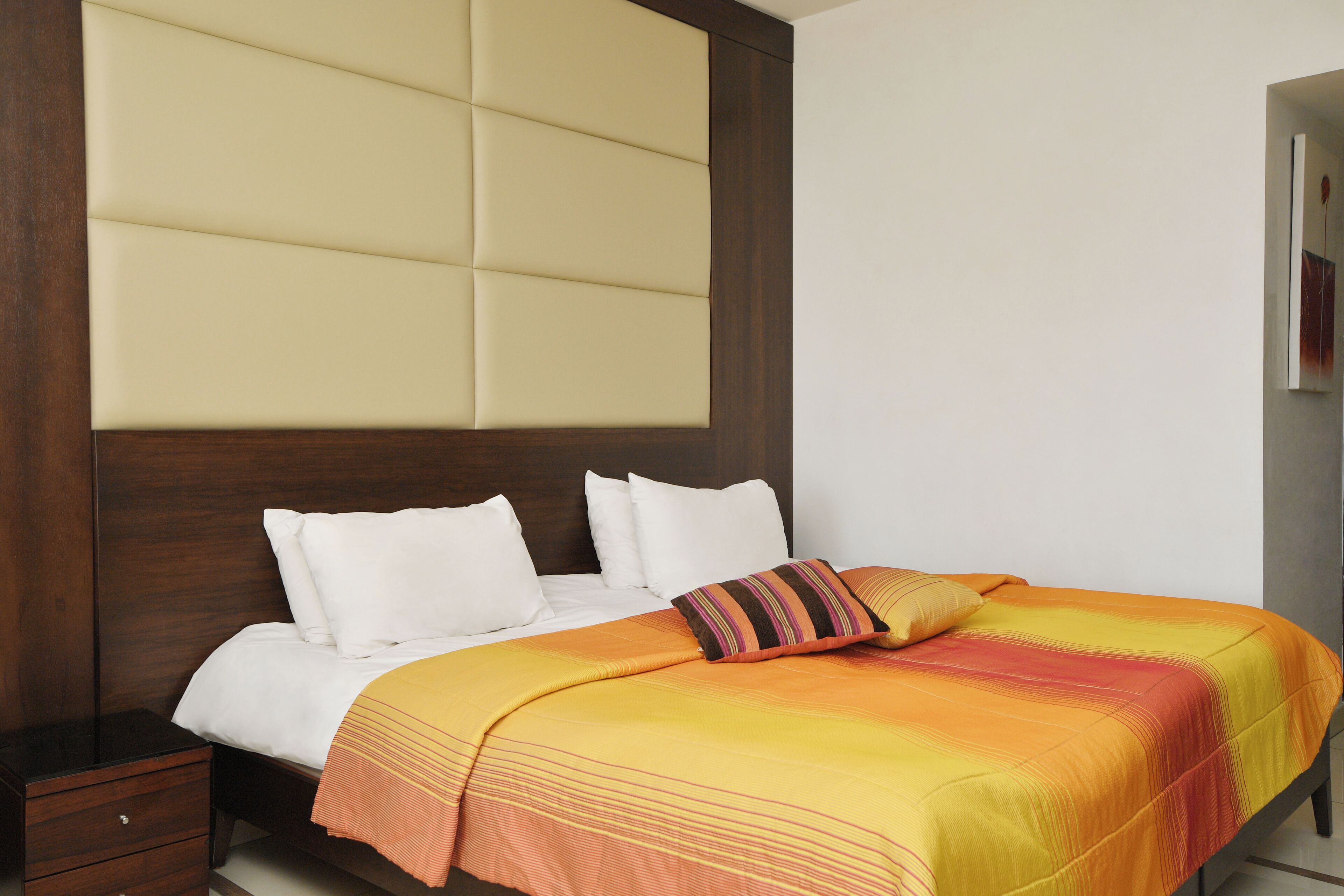 A hotel room with a bed, wooden headboard, and a nightstand.