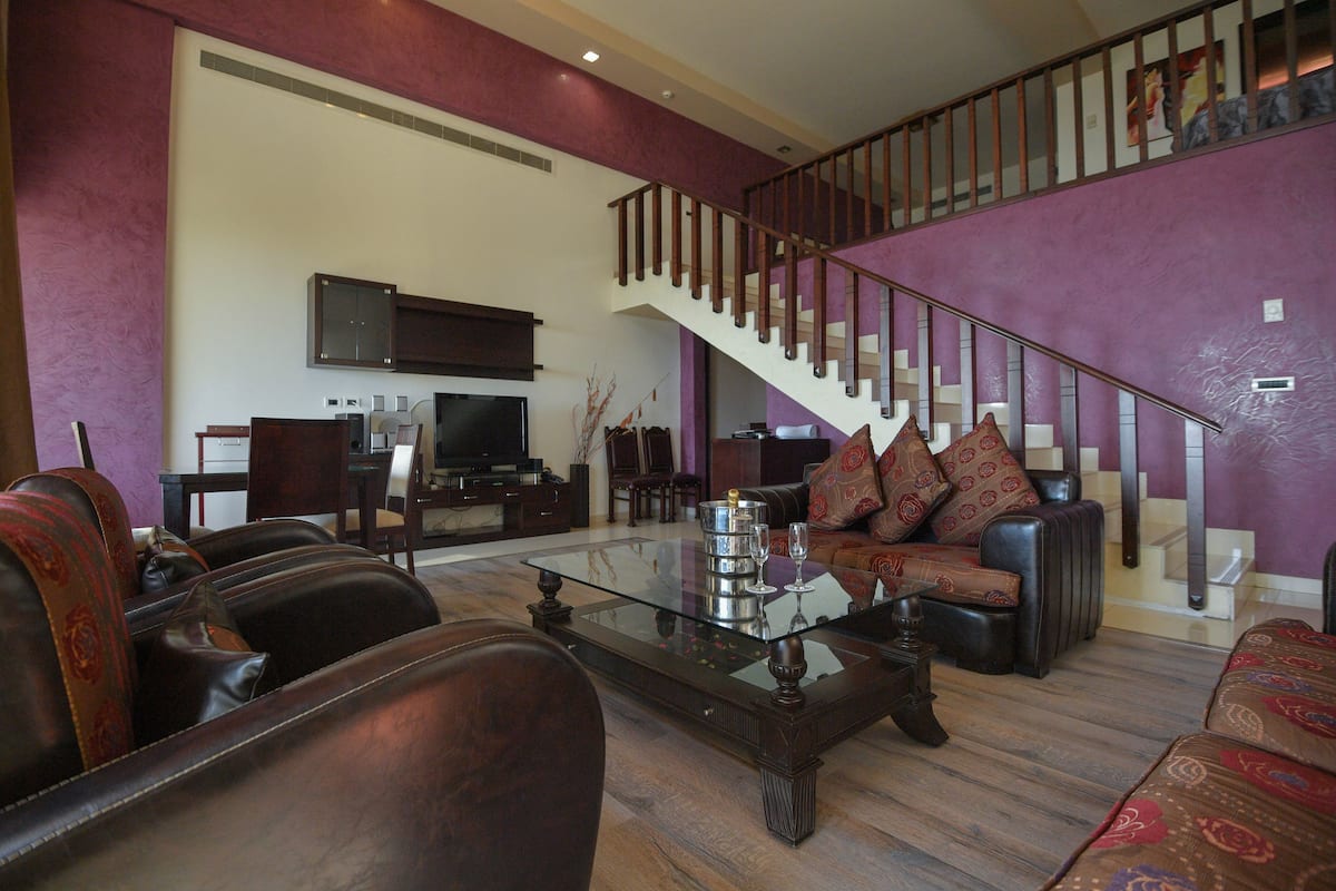 A spacious living room with leather sofas, a glass coffee table, and a staircase leading to an upper level.