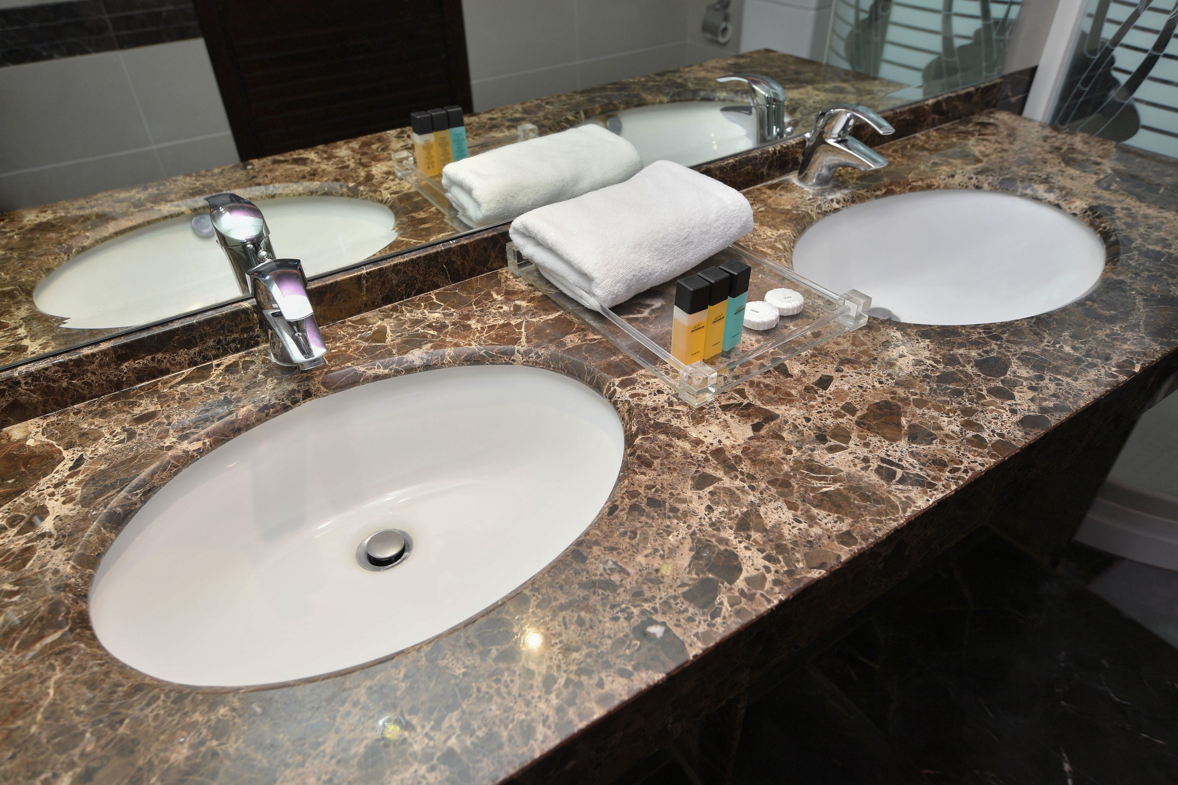 A bathroom with two sinks, a mirror, and a towel rack.