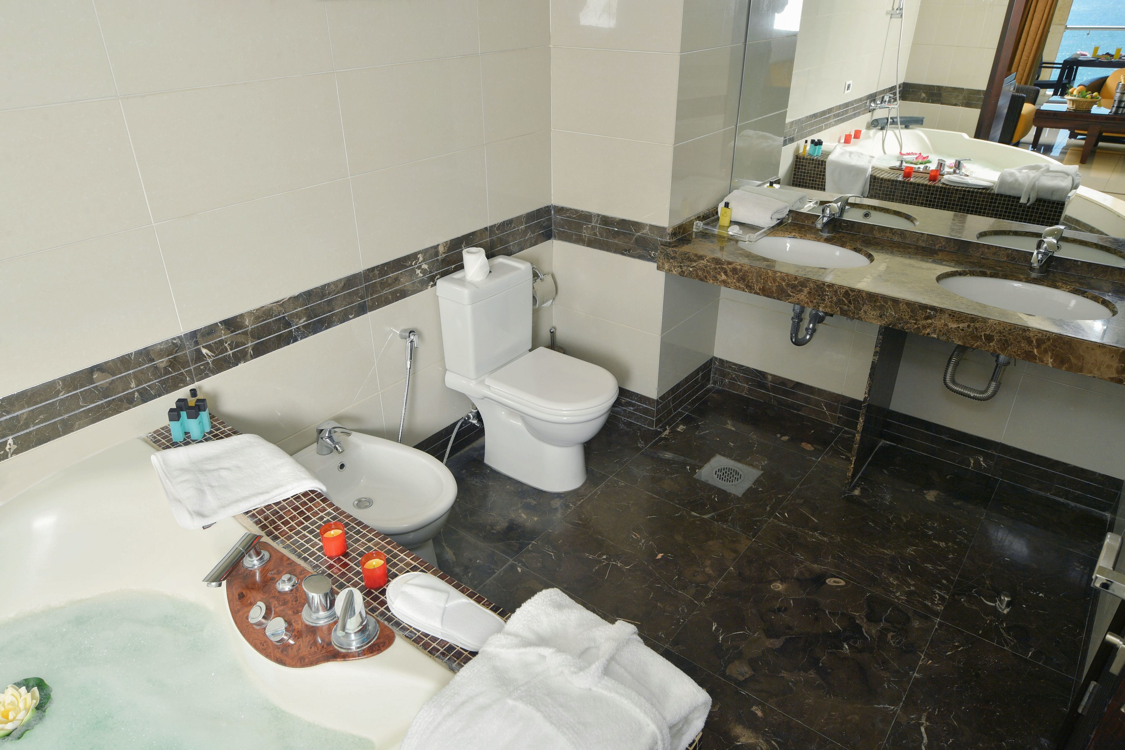A bathroom with a bathtub, two sinks, a toilet, and a mirror.