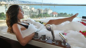 A woman relaxing in a bathtub with a city view. - Hollywood Inn Hotel (Ghazir)