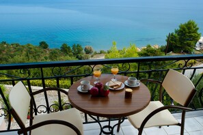 Mesa de madeira redonda com uma mesa de café da manhã em varanda com vista para um corpo de água.