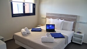 A neatly made bed with a laptop, towels, and a book on a bedside table. - Villa Contessa (Zakynthos)