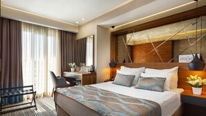 A hotel room with a large bed, a desk, and a chair. - Artur Hotel (Çanakkale)