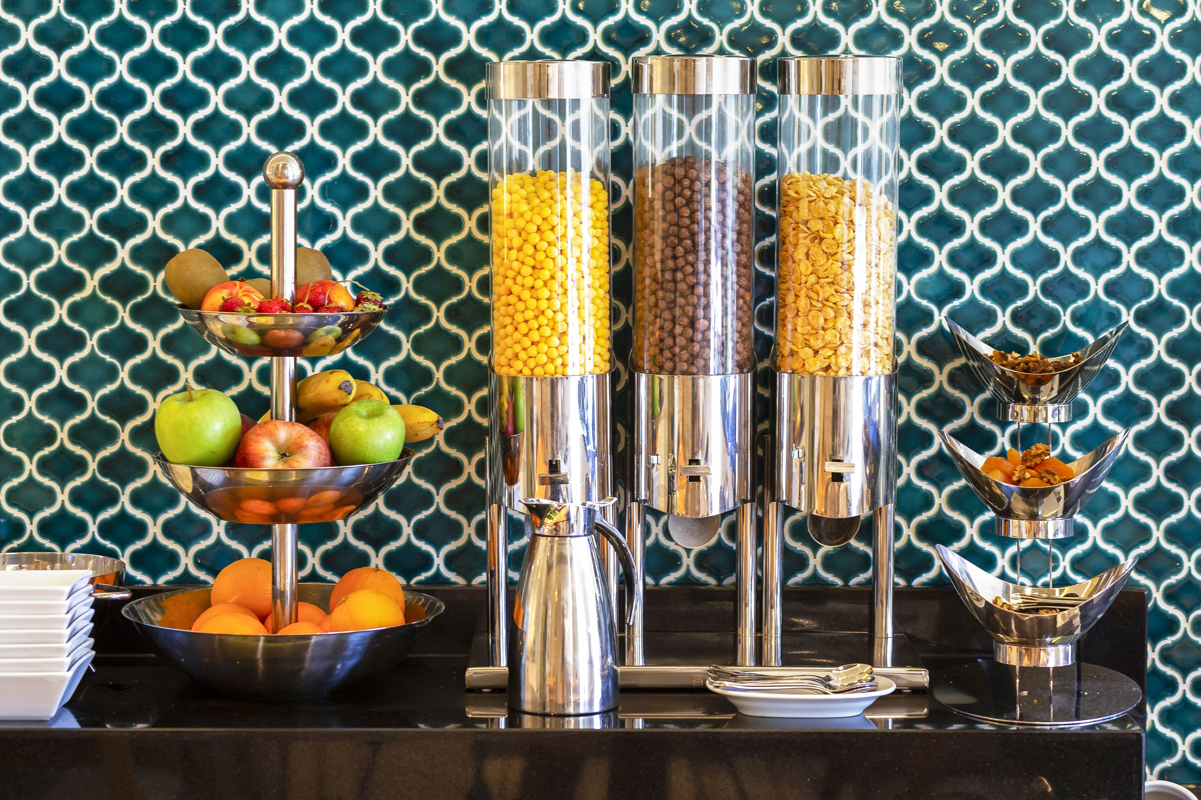 Montaje de un bufé de desayuno con diversos alimentos y una máquina de café.
