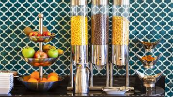 Montaje de un bufé de desayuno con diversos alimentos y una máquina de café.