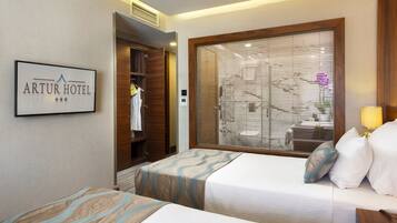 A hotel room with two beds, a large window with blinds, a wardrobe, and a sign on the wall.
