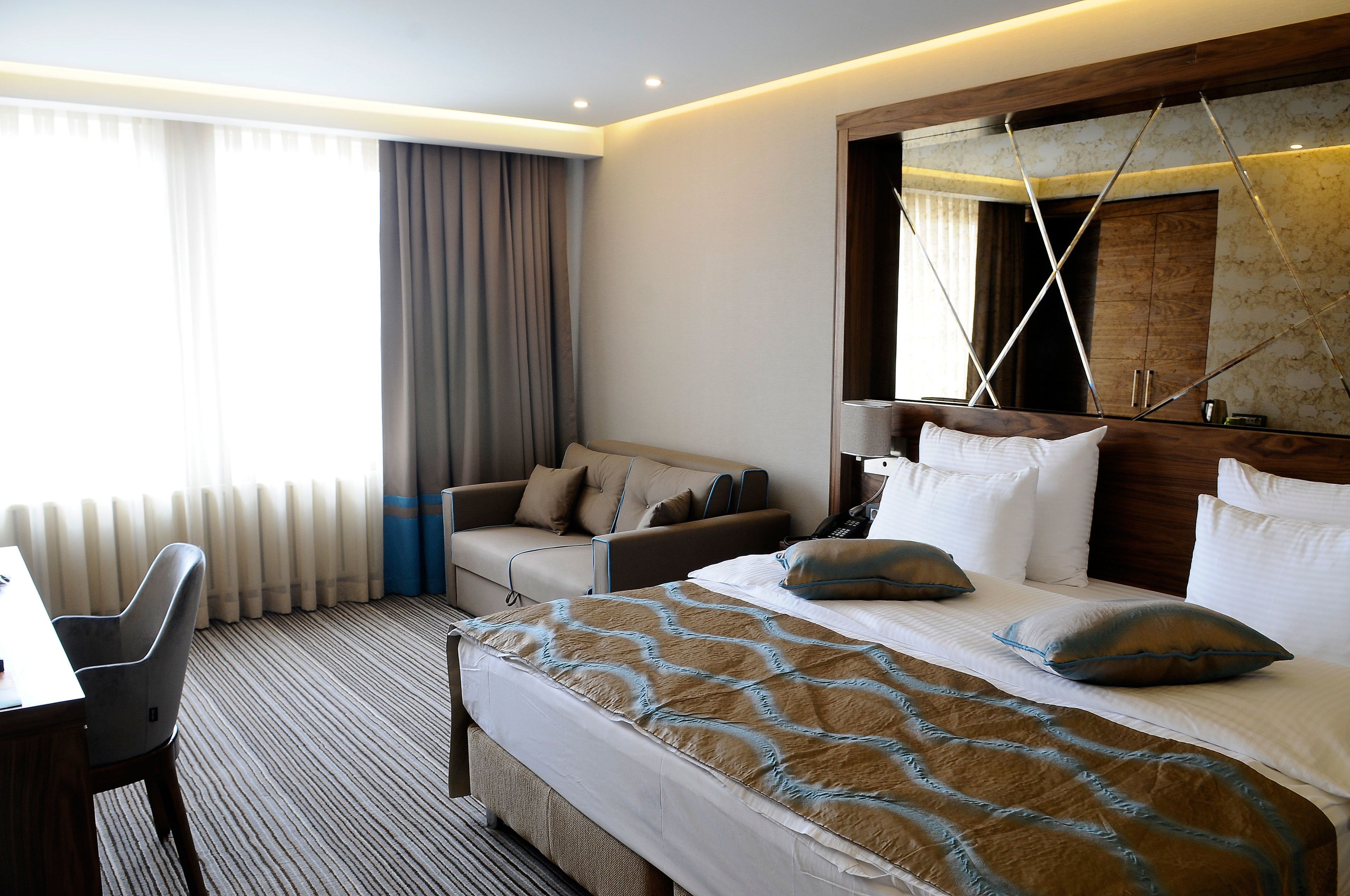 Una habitación de hotel con una cama grande, un escritorio y un sofá.