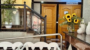 A lobby area with a staircase, a cafeteria sign, and a bench with a vase of sunflowers. - Hotel Reyesol (Fuengirola)