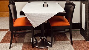A dining area with a table and two chairs, a white tablecloth, and a decorative door with intricate designs. - Hotel Reyesol (Fuengirola)