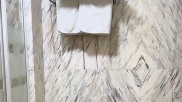 Une salle de bain avec un mur décoré d’un motif imitant le marbre, un bidet, des toilettes et un porte-serviettes.