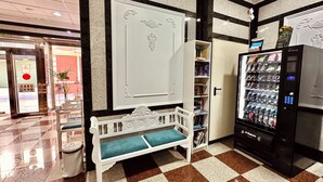 A lobby with a checkered floor, a vending machine, a white bench, and a door with a red circle sign. - Hotel Reyesol (Fuengirola)