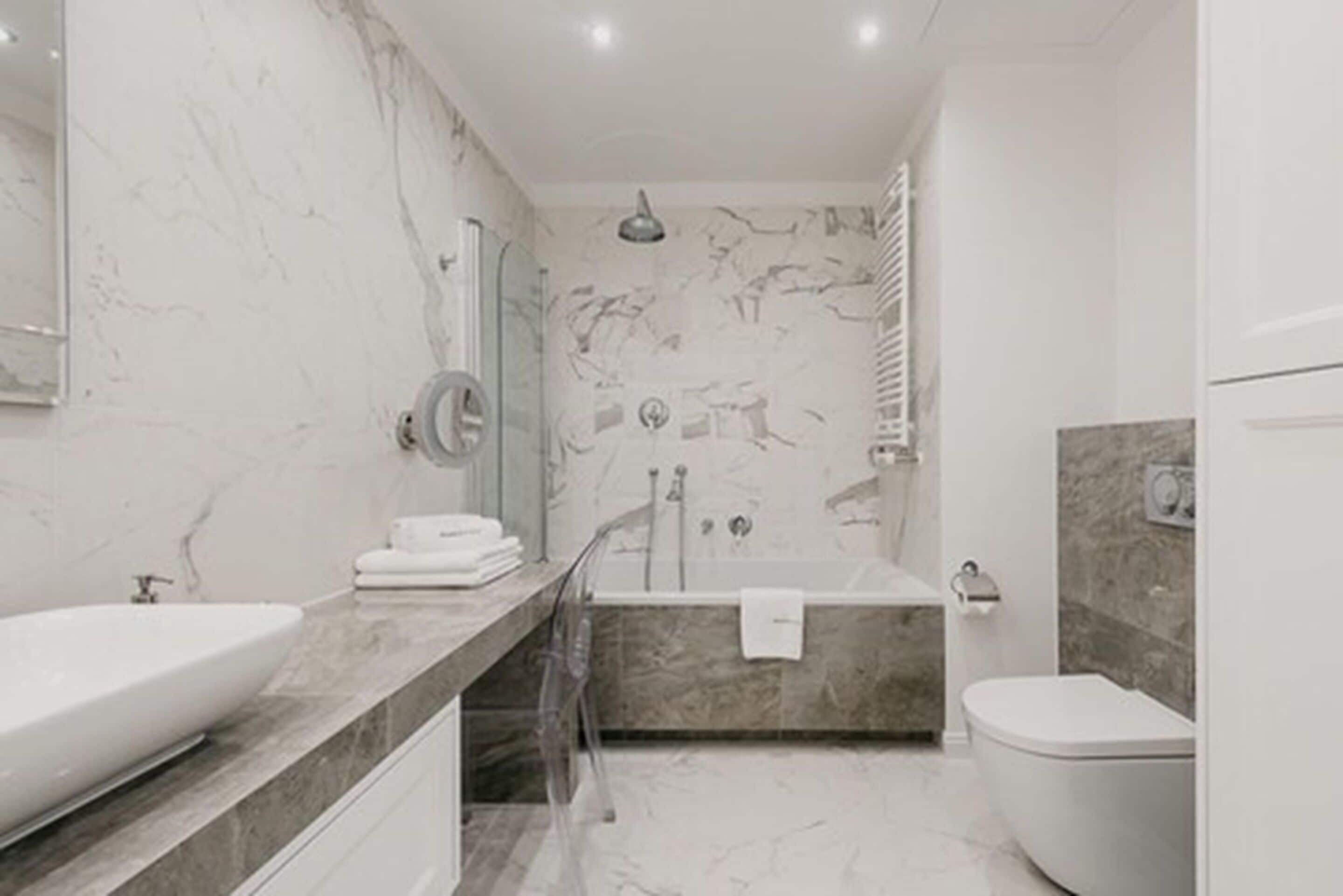 A modern bathroom with a large bathtub, a separate shower area, and a toilet.