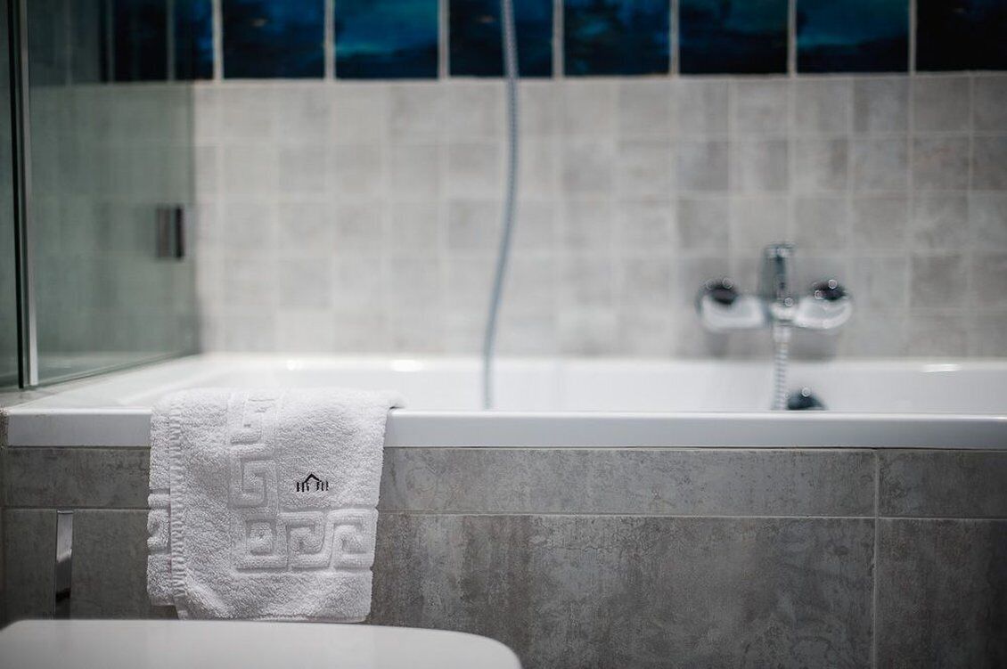 A modern bathroom with a bathtub, a glass shower enclosure, and a white towel on the edge.