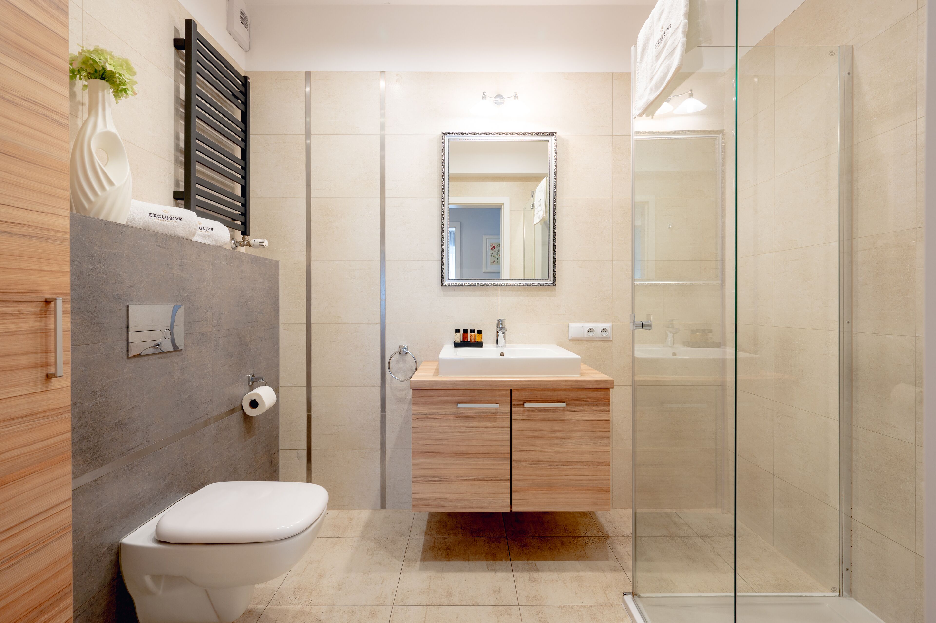Une salle de bain moderne comprenant des toilettes, un lavabo avec un miroir au-dessus, et une douche à parois de verre.