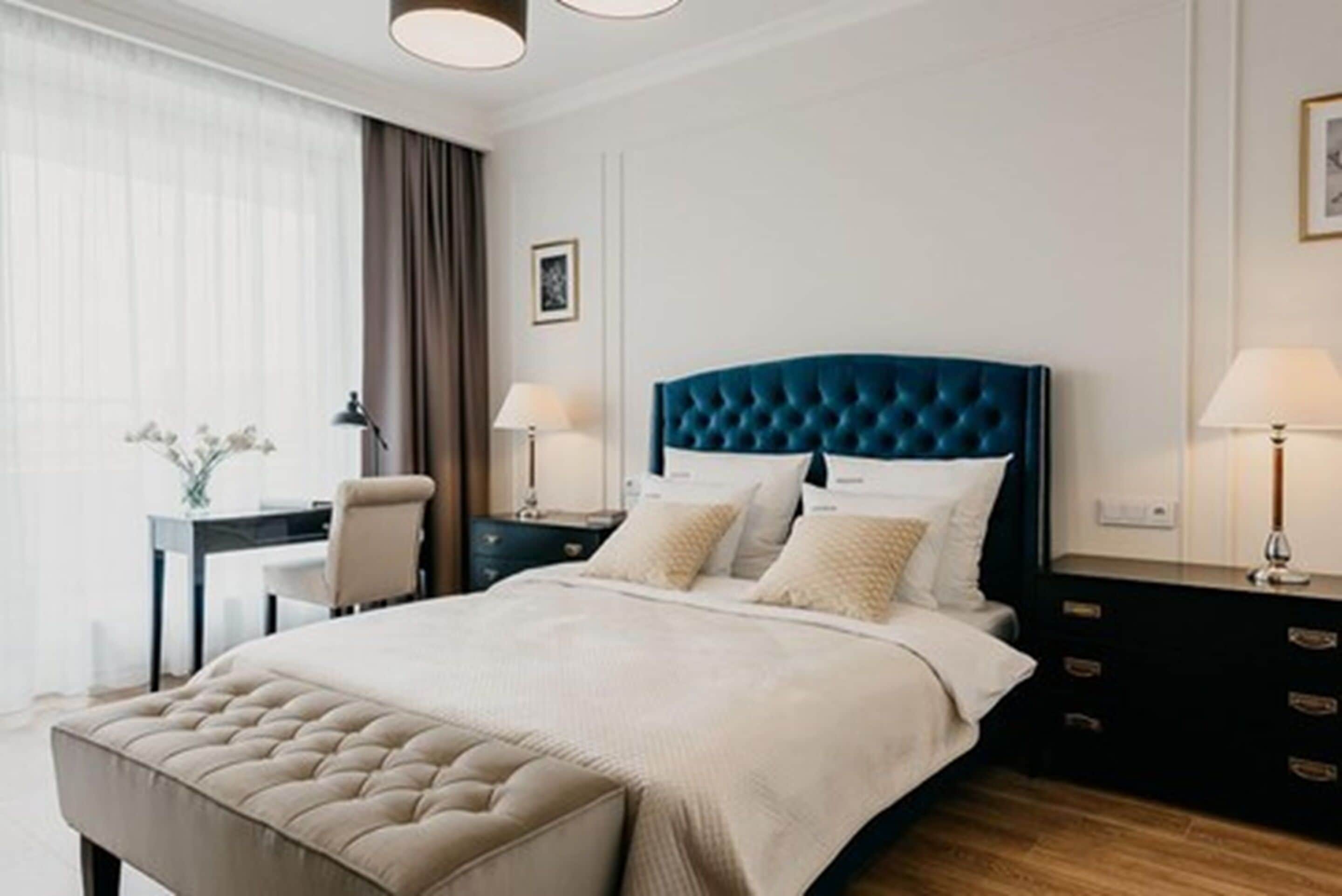 A modern hotel room with a large bed, a desk, and a chair.