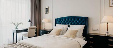 A modern hotel room with a large bed, a desk, and a chair.