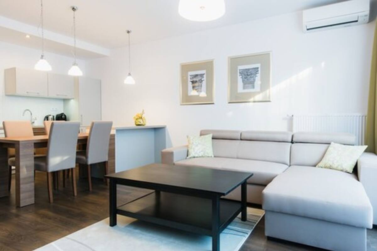 A modern living room with a sofa, a coffee table, and a dining area with chairs and a table.