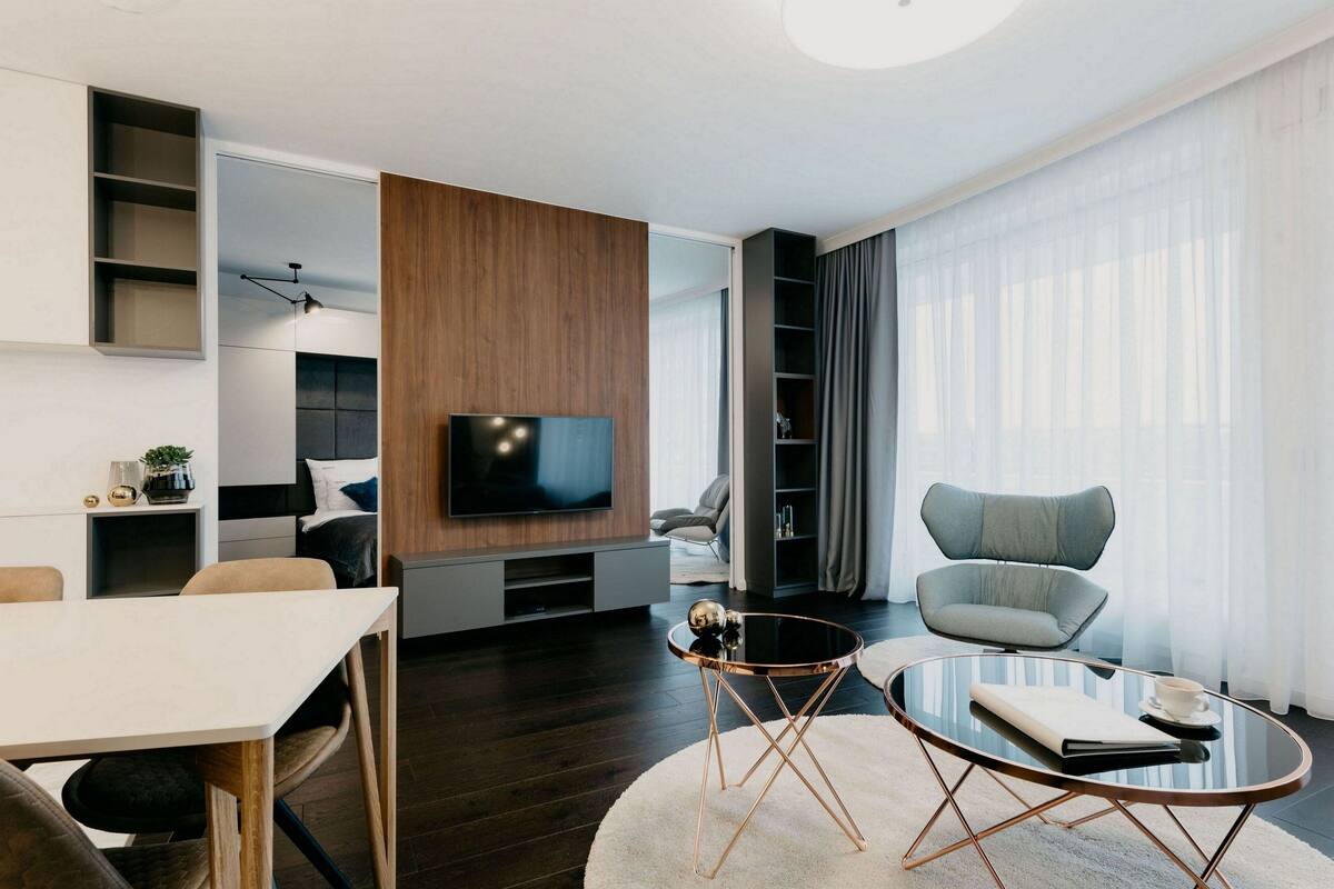 A modern living room with a flat-screen TV, a round coffee table, and a comfortable seating area.