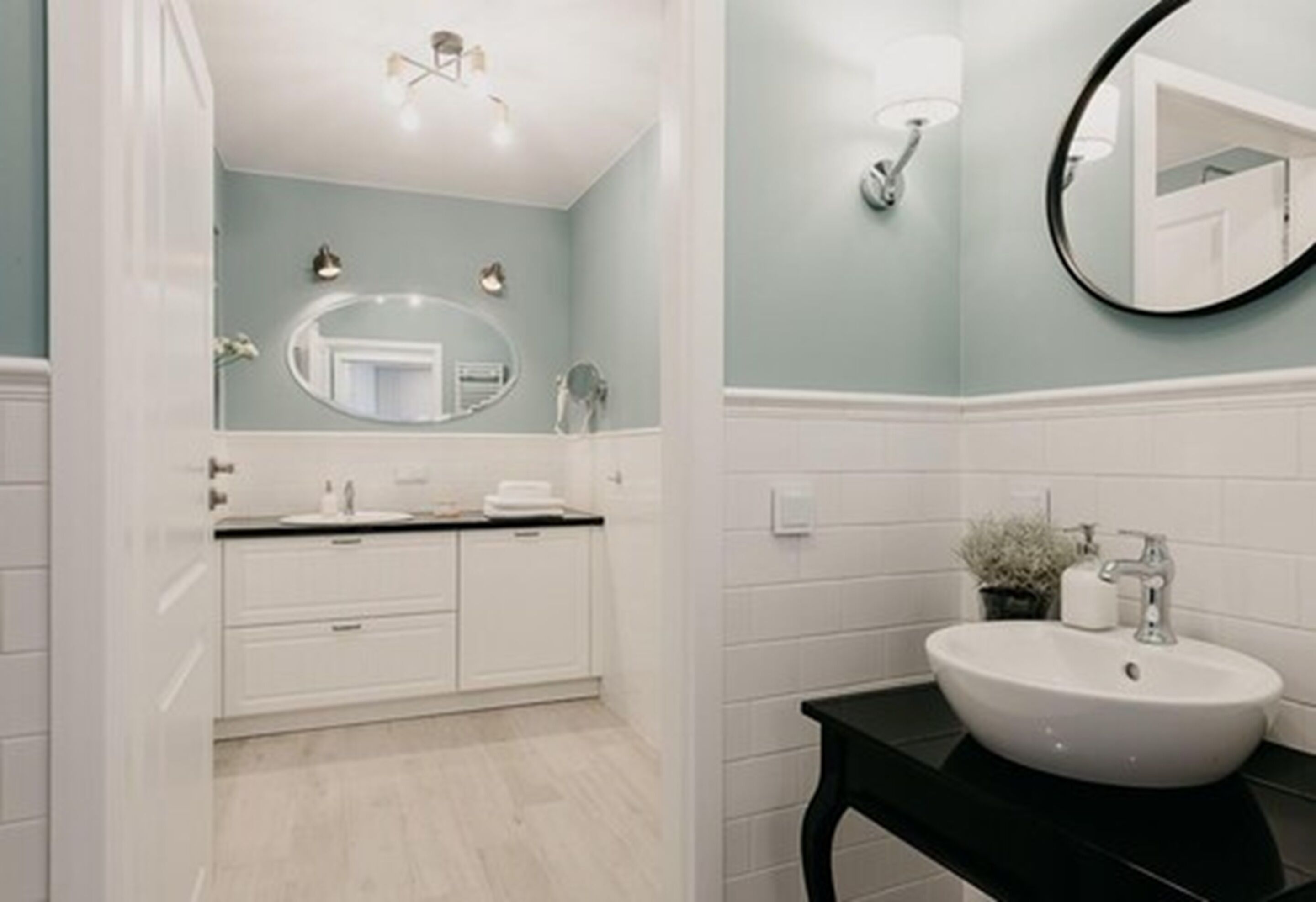 A bathroom with a white vanity, a round mirror, and a black countertop sink.