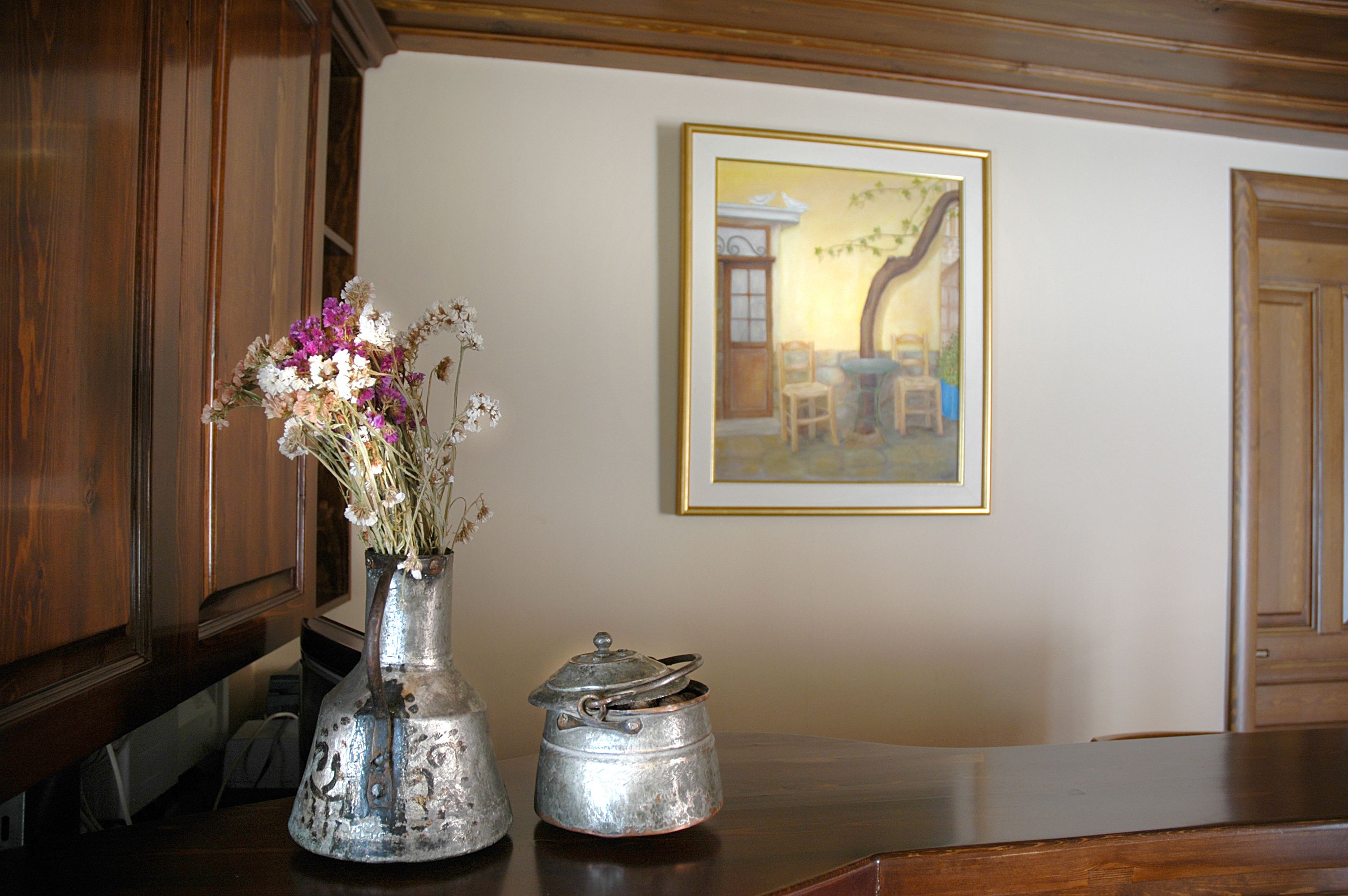 A kitchen counter with a metal vase of flowers and a metal pot.