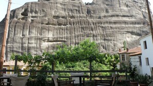 A patio with outdoor seating and a view of a large rock formation. - Guesthouse Sotiriou (Kalabaka)