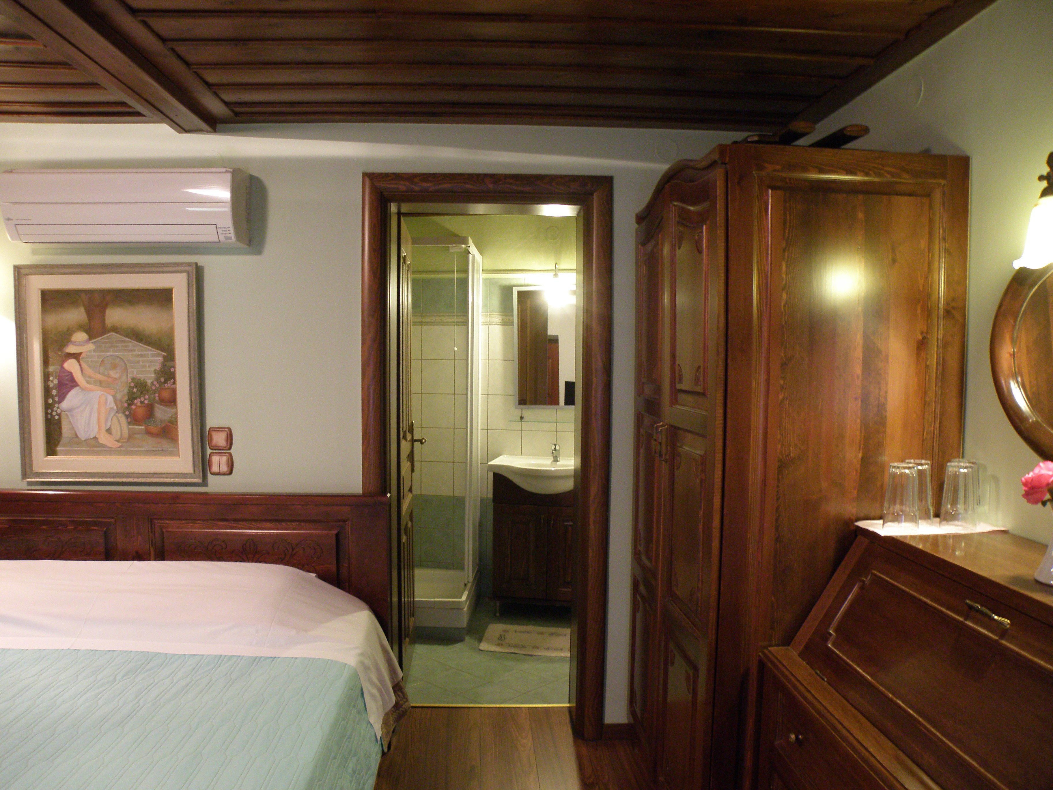 Habitación de hotel con cama, armario de madera, baño con lavabo y un cuadro en la pared.
