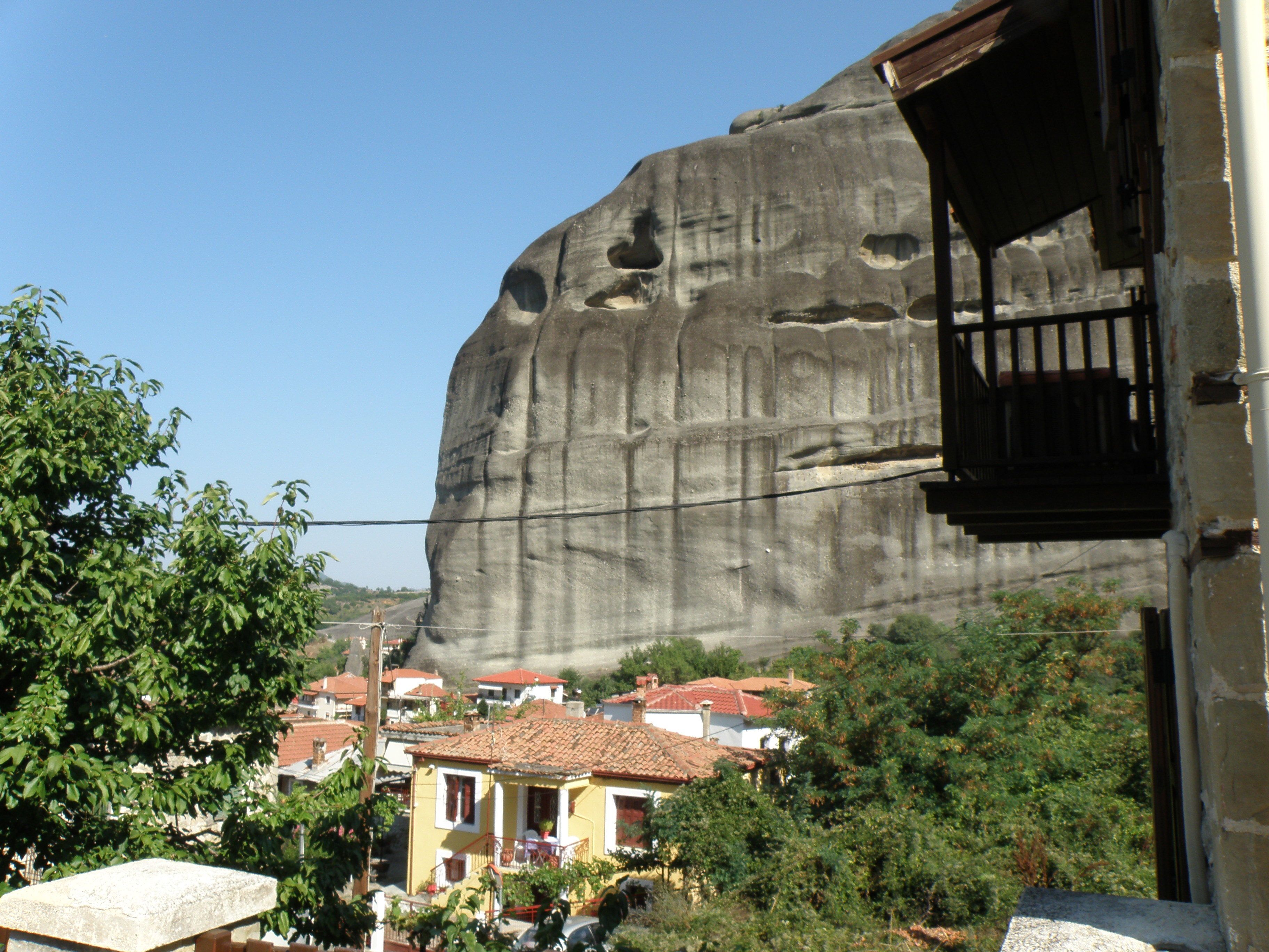 A large rock formation with a balcony overlooking a residential area with houses and greenery.