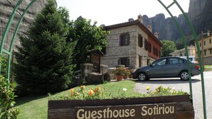 A sign for 'Guesthouse Sotiriou Petrino' with a stone building in the background. - Guesthouse Sotiriou (Kalabaka)