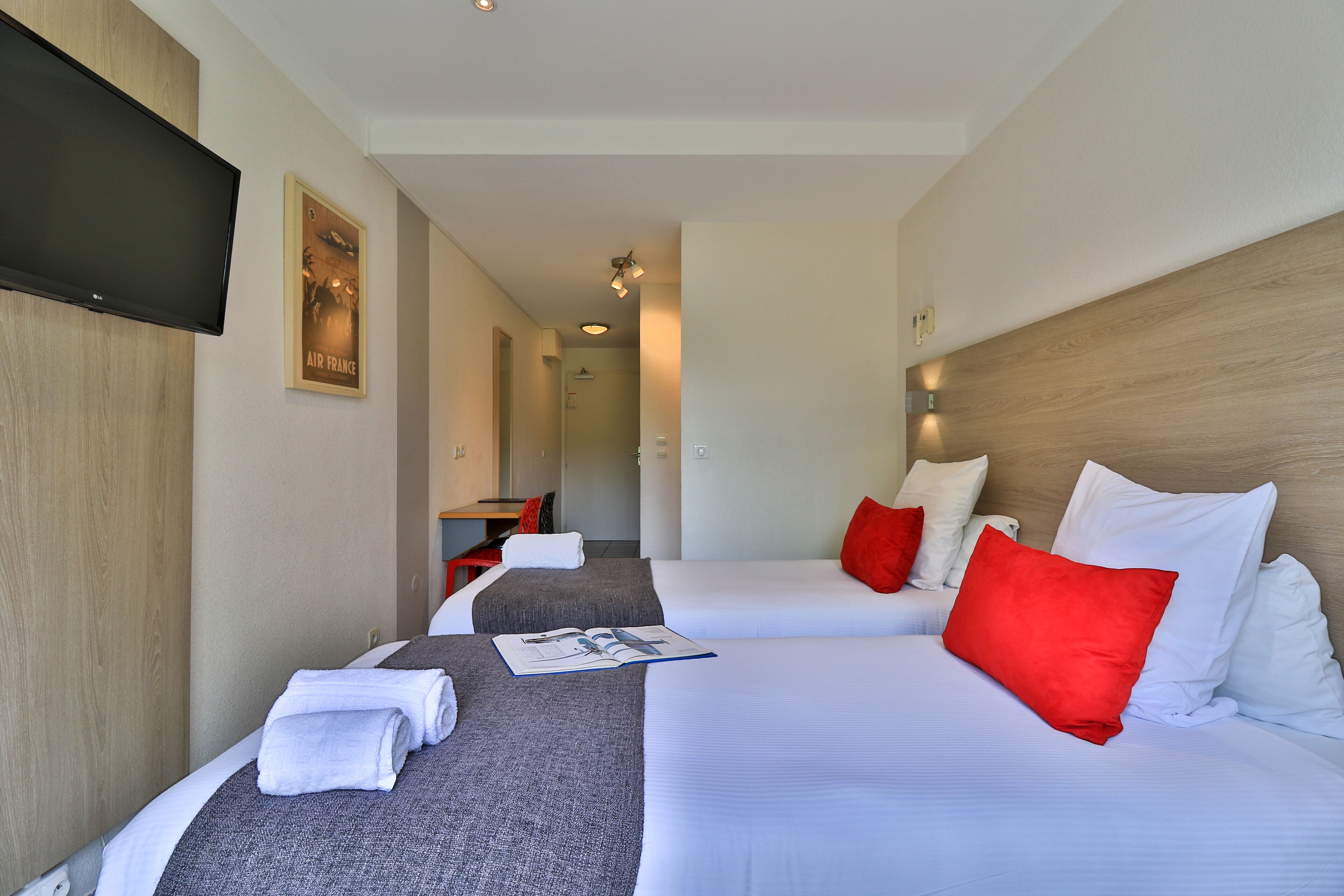 Habitación de hotel con dos camas, un televisor, un cartel y un escritorio.