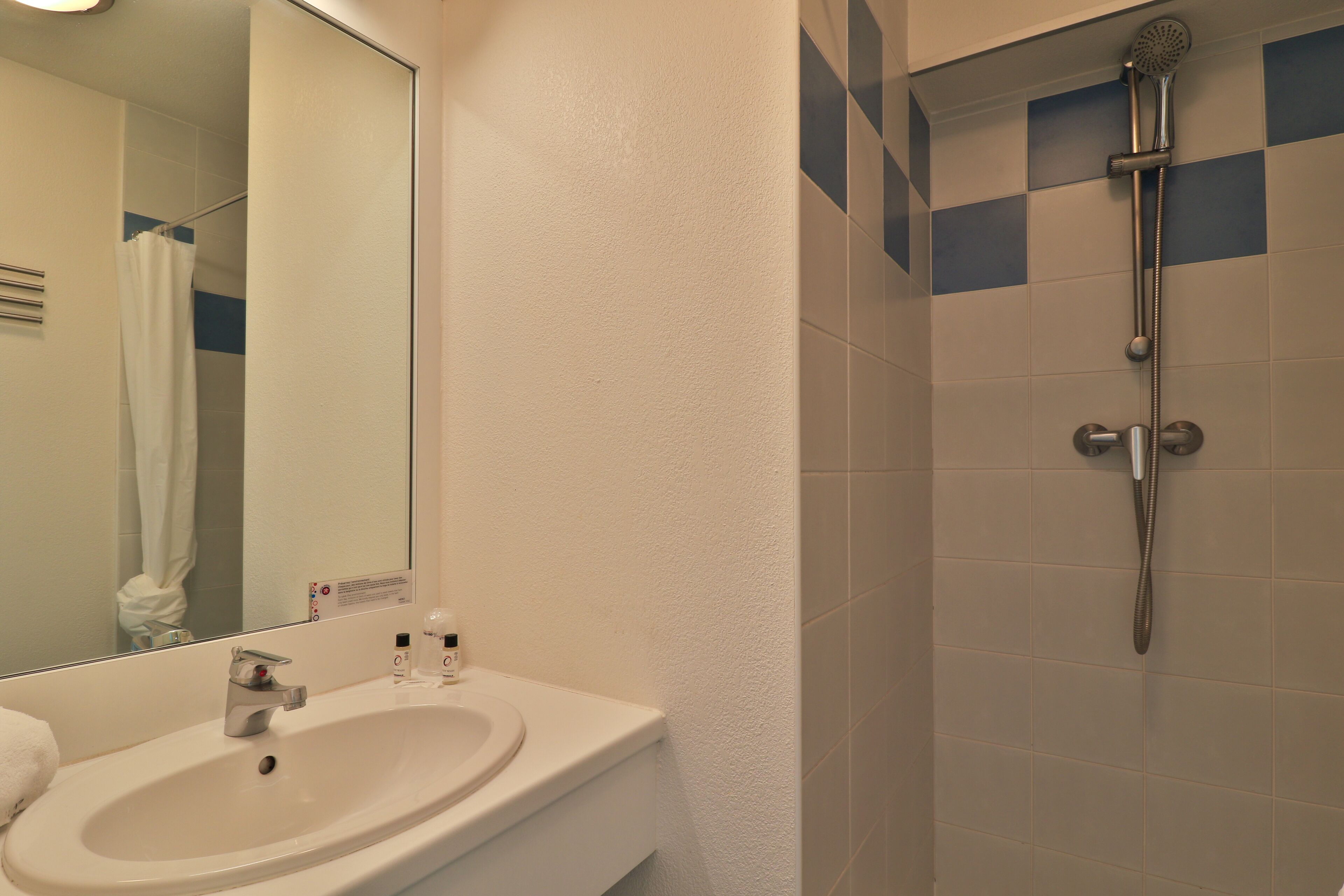 Un baño con lavabo, espejo y ducha.