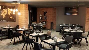 A restaurant with multiple tables and chairs, a world map on the wall, and a clock on the right.