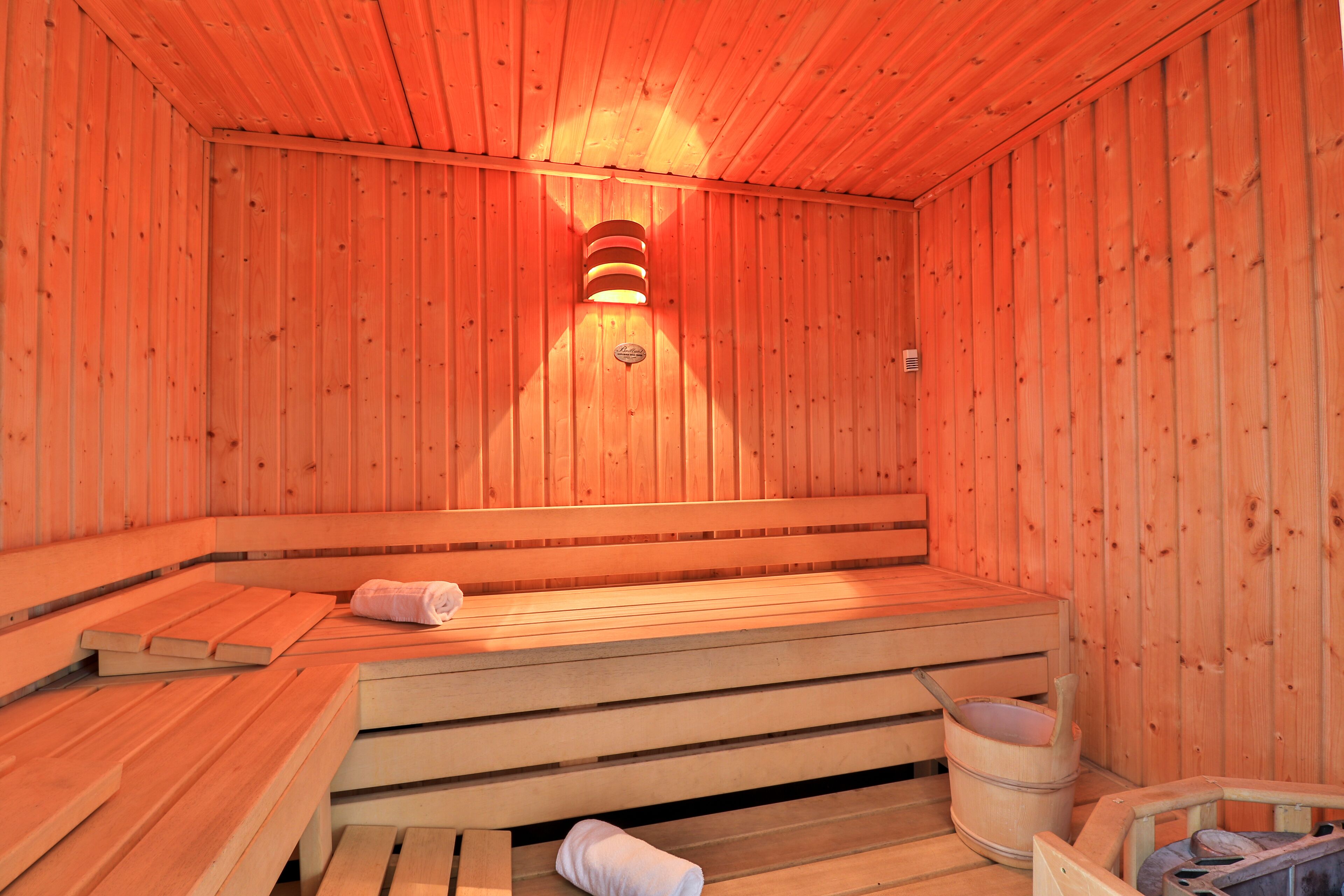 Een houten sauna met banken en een emmer.