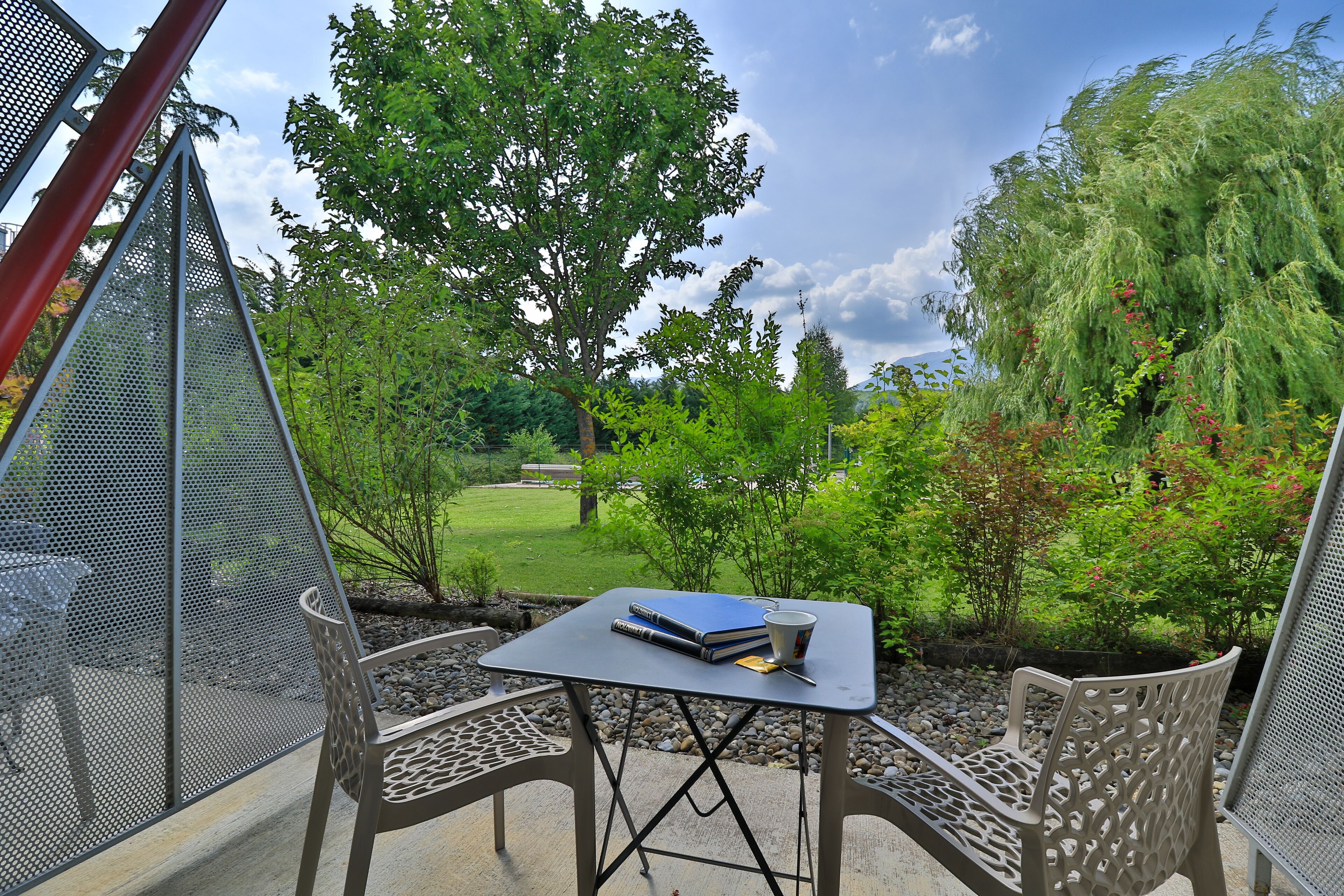 A patio with a table and chairs, a book, and a cup.