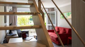 A modern interior with a staircase, a red sofa, and a laptop on a table.