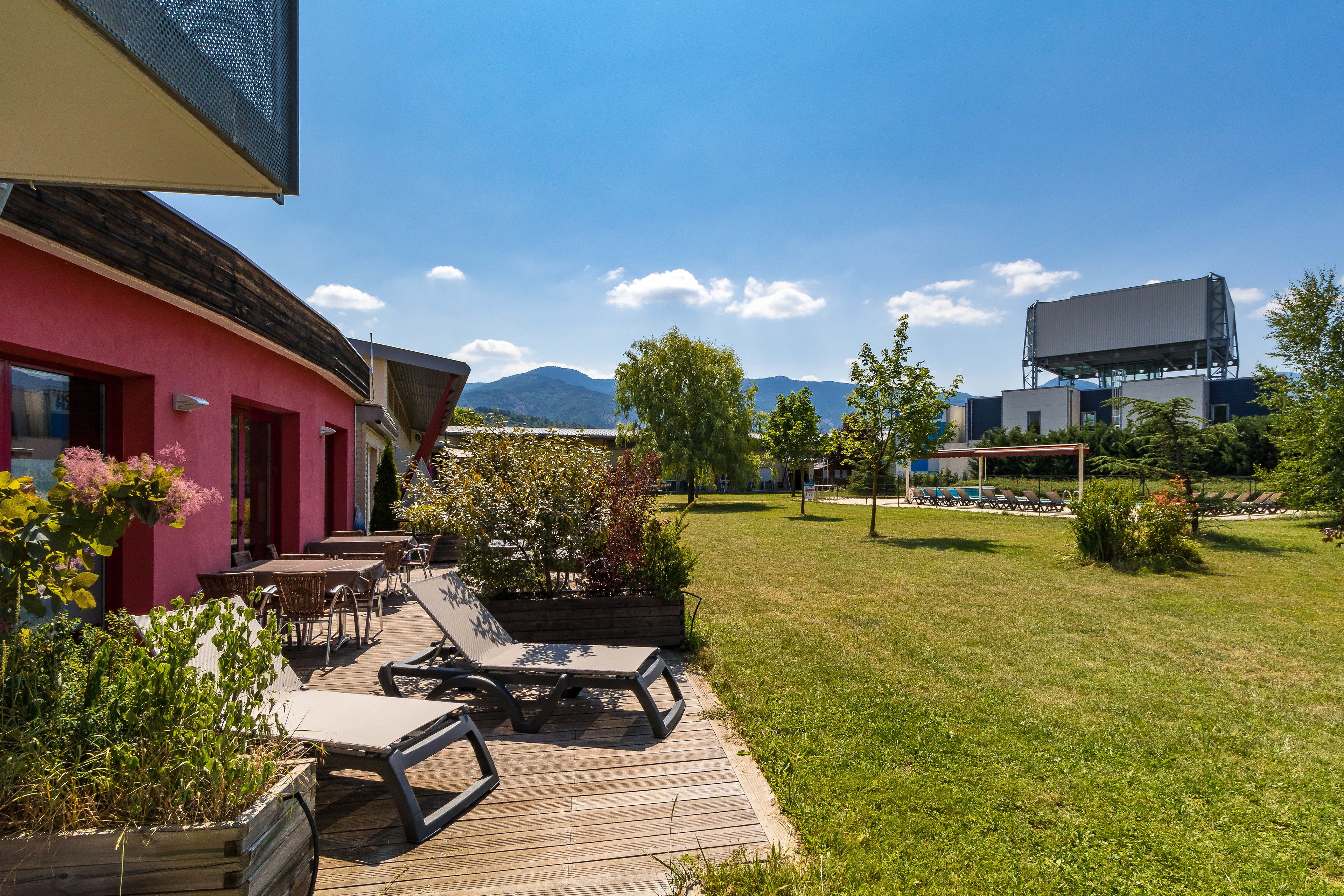 A patio with outdoor seating, a grassy lawn, and a view of mountains.