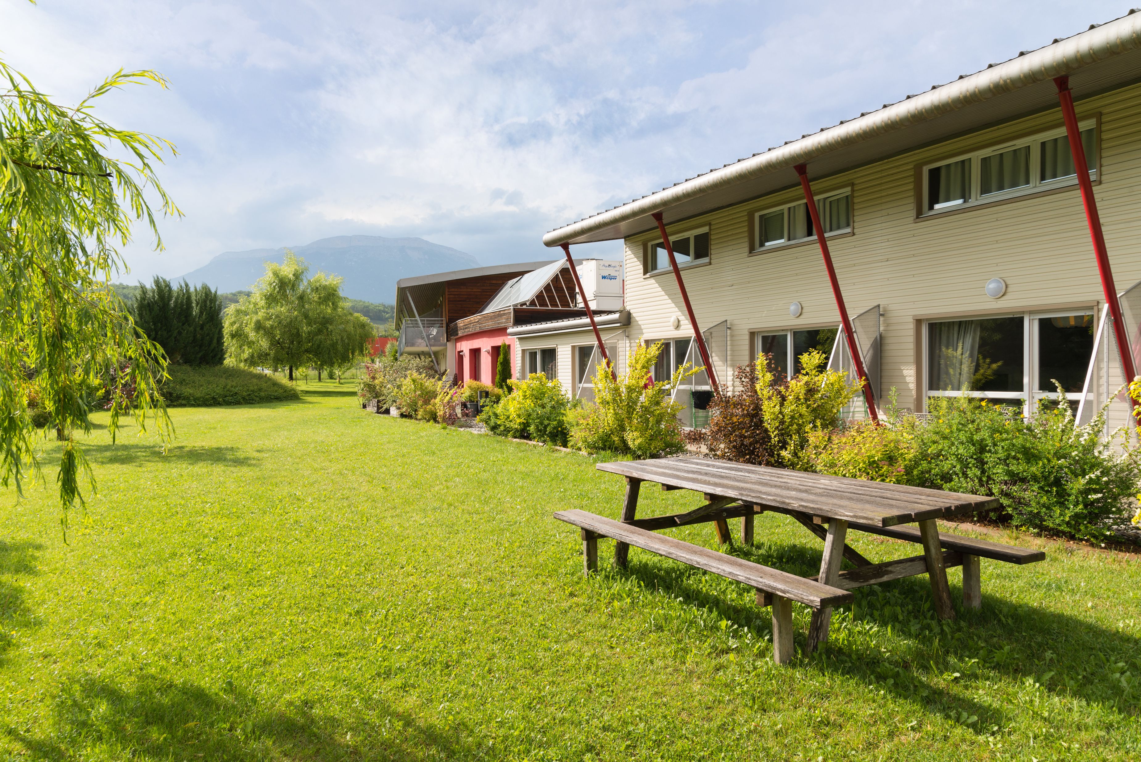 Een rij eenlaags huizen met een gazon en een picknicktafel op de voorgrond.