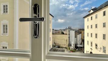A window with a metallic handle and a view of a street with buildings.