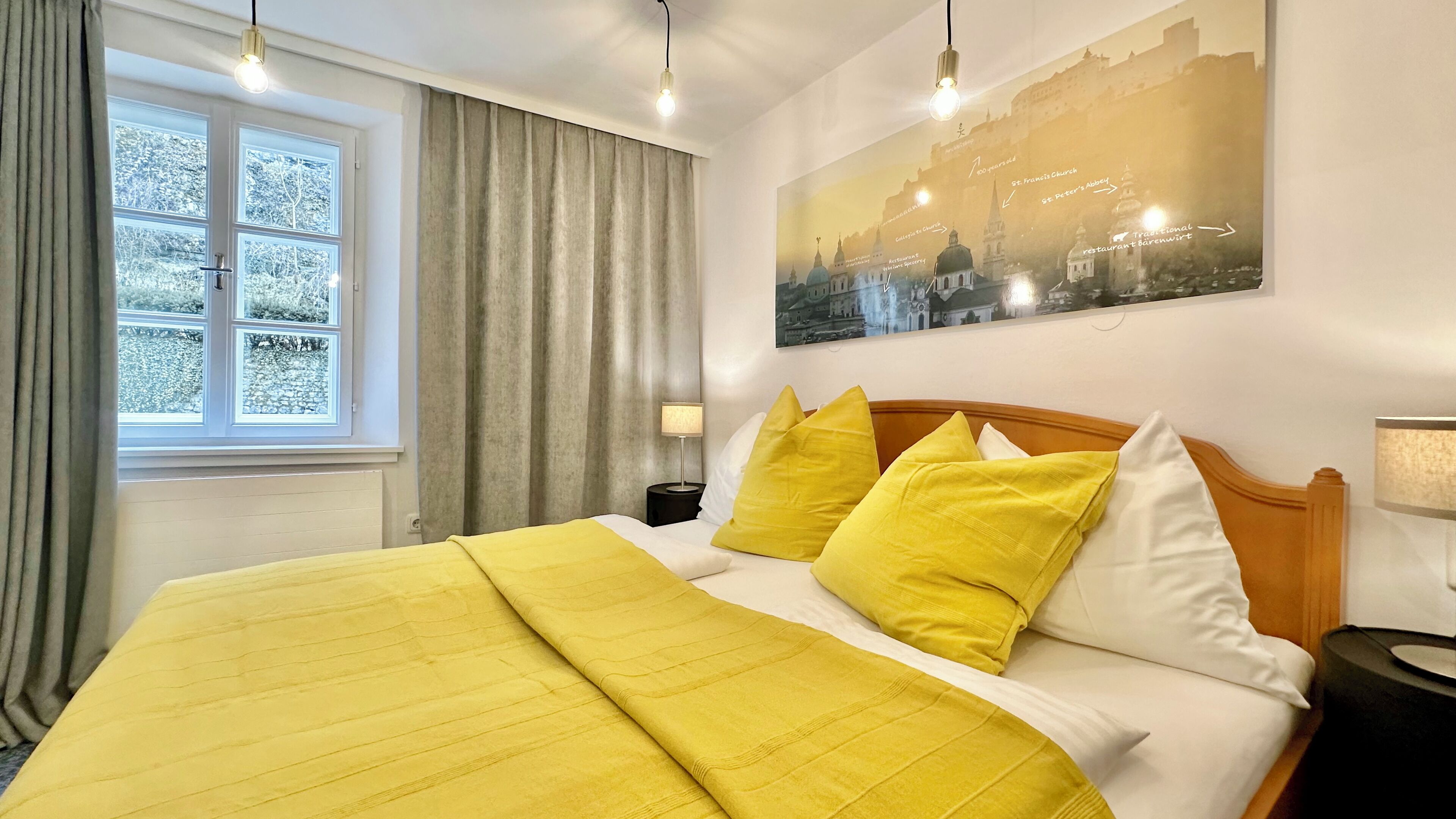 A hotel room with a large bed, a nightstand, a lamp, and a window with curtains.